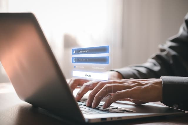 Man typing on a laptop showing a virtual screen